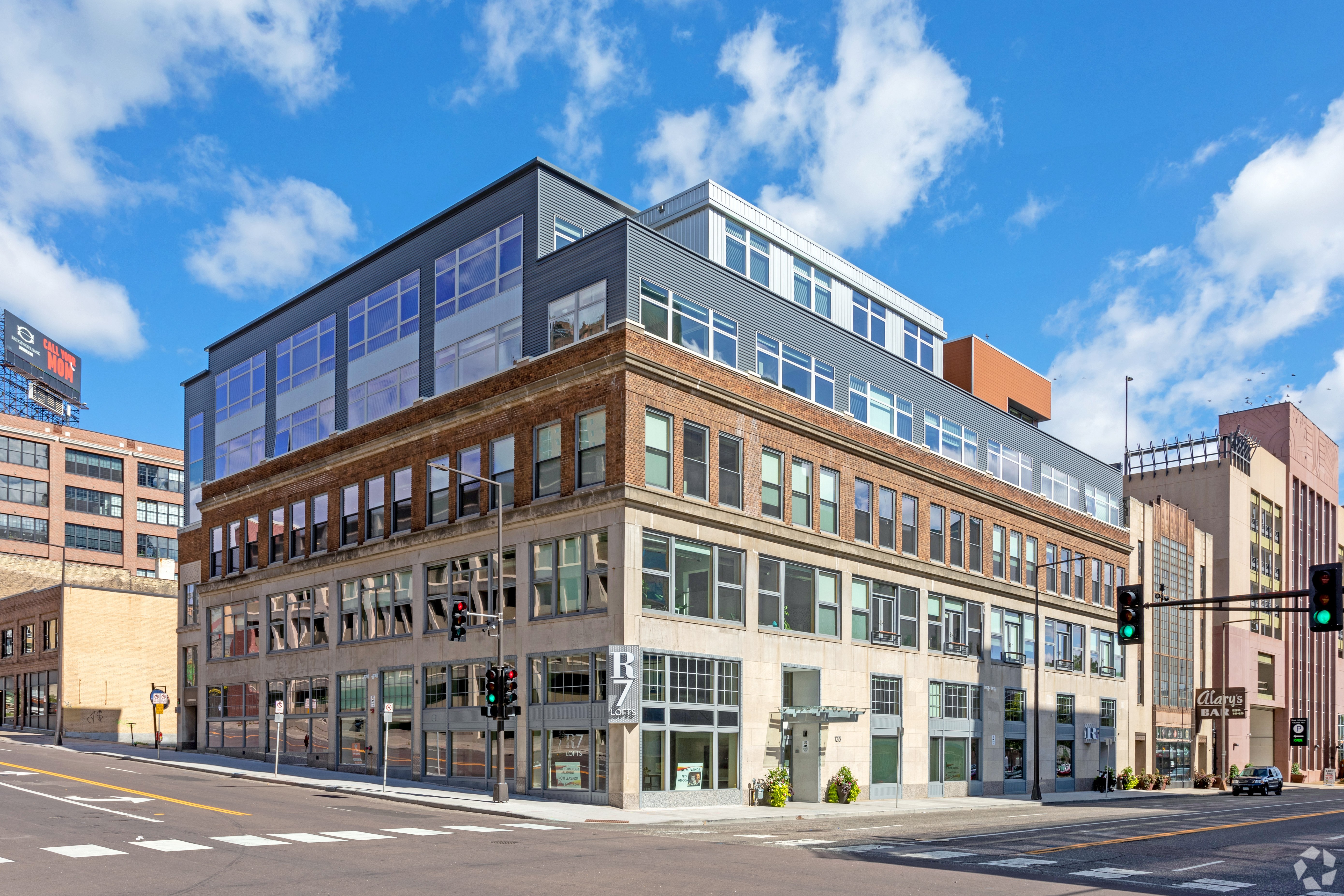A modern building with a glass facade is situated on a street corner.